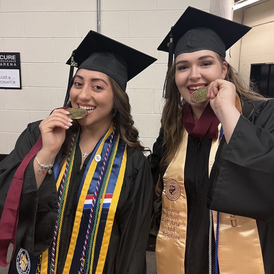 Two Thomas Edison State University graduates biting their medals.